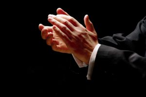 Picture of two hands clapping protruding from a suit with fingers lit